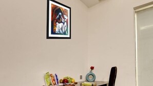 A corner office with a desk, chair, framed artwork, and a small table with snacks. - Good Times (New Delhi)