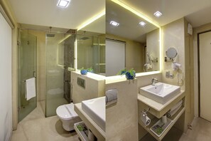 Un baño moderno con ducha envuelta en vidrio, un lavamanos blanco y un espejo grande.