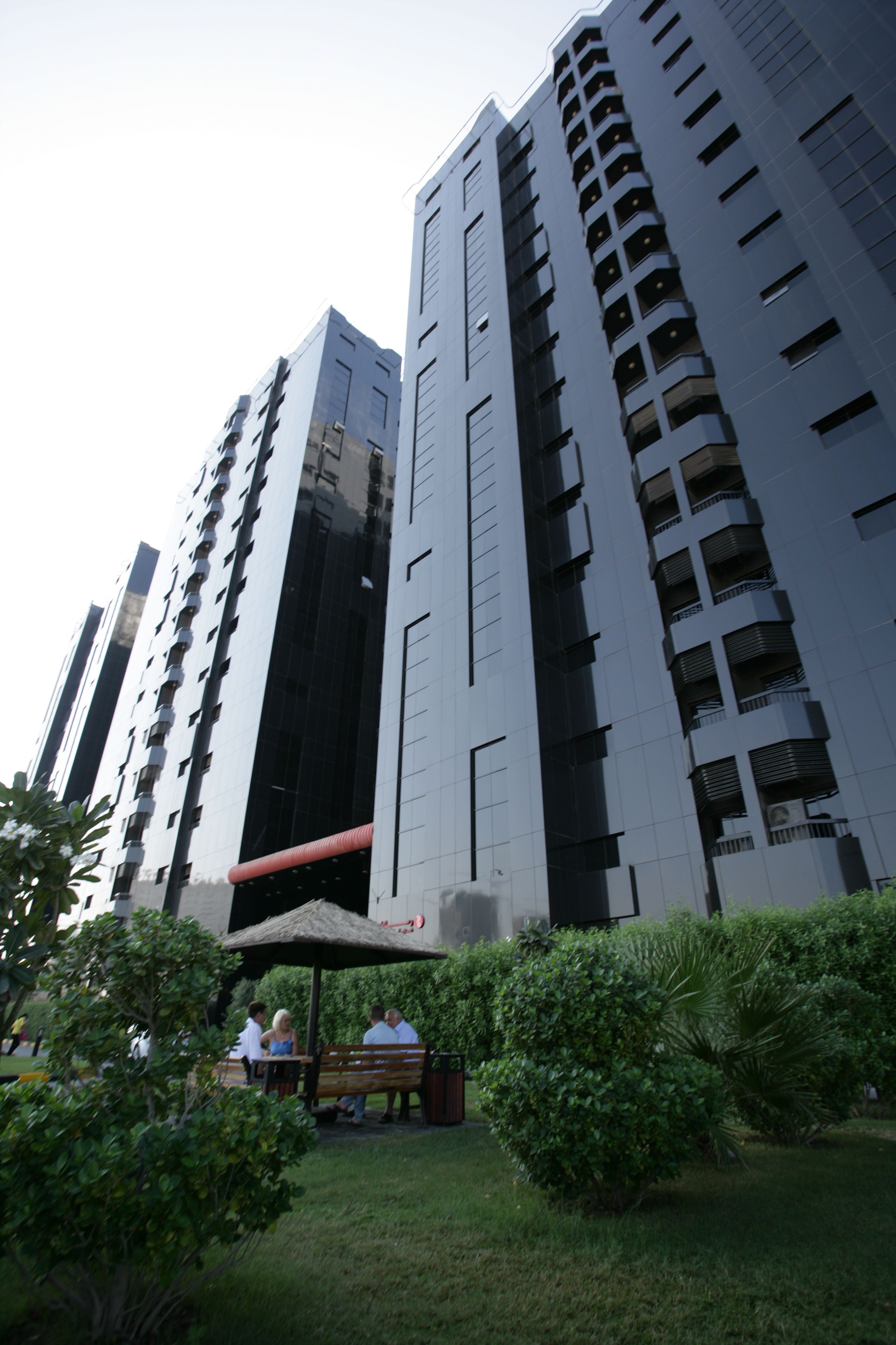 A high-rise building with multiple balconies and a central open area with benches and greenery.