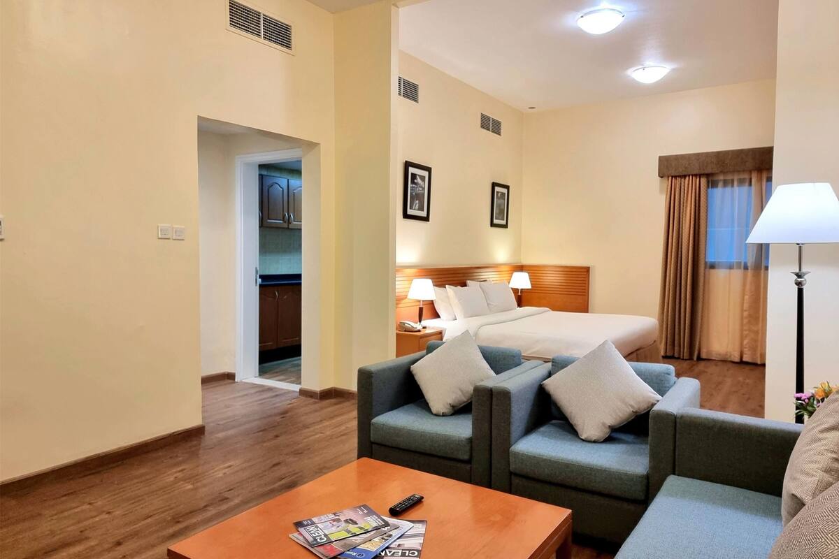 Une chambre d’hôtel avec un lit, deux canapés, une table basse et une lampe.