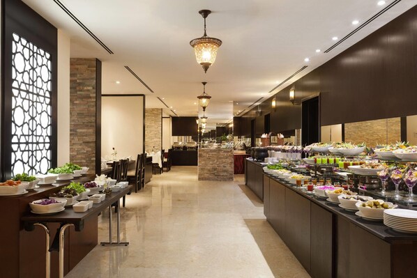 A buffet with various food items and a seating area with tables and chairs.