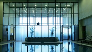 Eine moderne Lobby mit einem Spiegelteich, einer Sitzgelegenheit und einer großen Glaswand mit Blick.