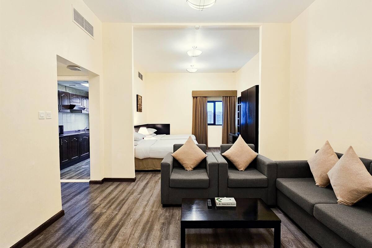 Une chambre d’hôtel comprenant un canapé, une table basse, un téléviseur, un lit et une vue sur la ville par la fenêtre.