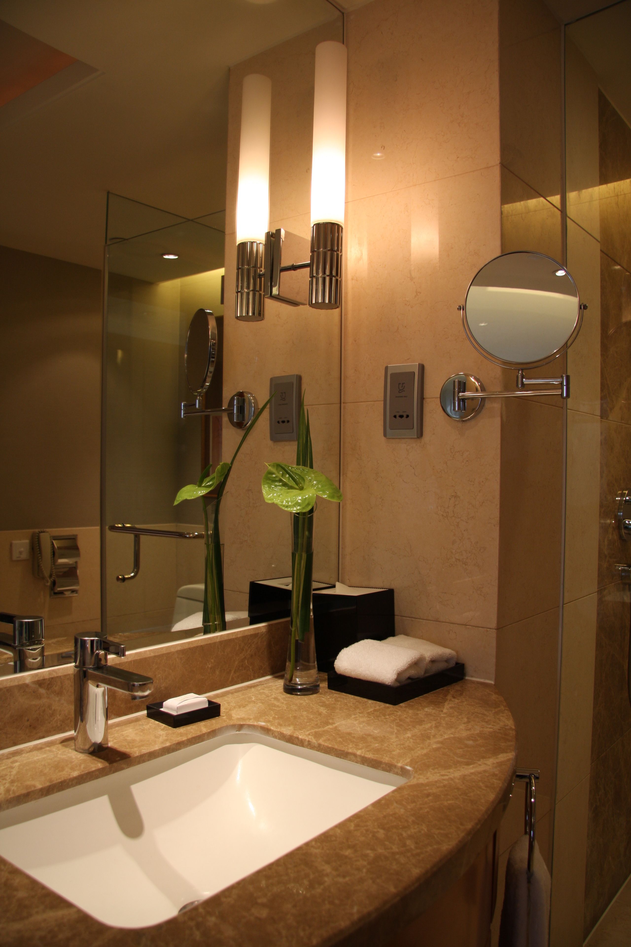 Un baño moderno con un espejo grande, un lavamanos y una cabina de ducha de vidrio.