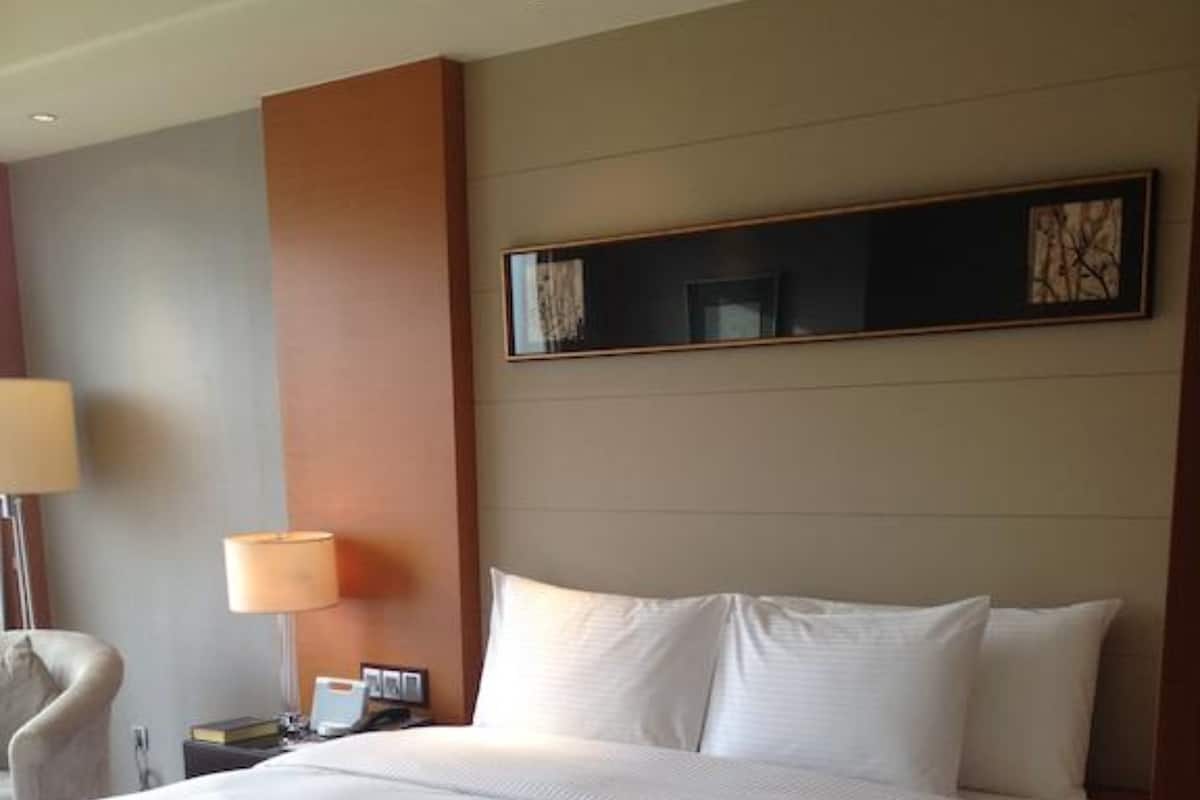 A hotel room with a large bed, a bedside table with a lamp, and a chair.