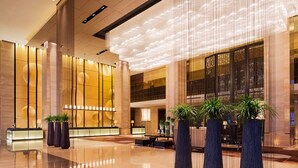 A spacious lobby with a polished floor, large seating area, and tall columns. - Wanda Realm Beijing (Beijing)