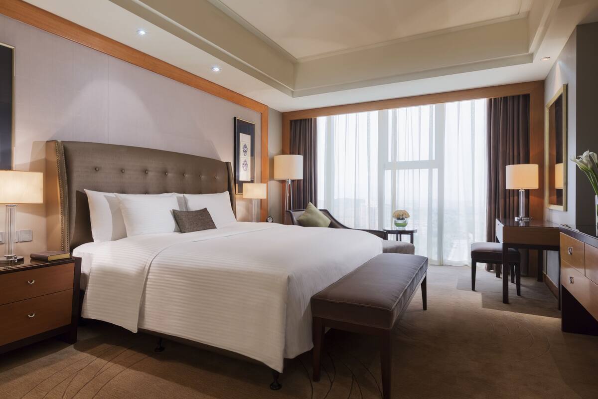 A hotel room with a large bed, bedside tables, a desk, and a chair.