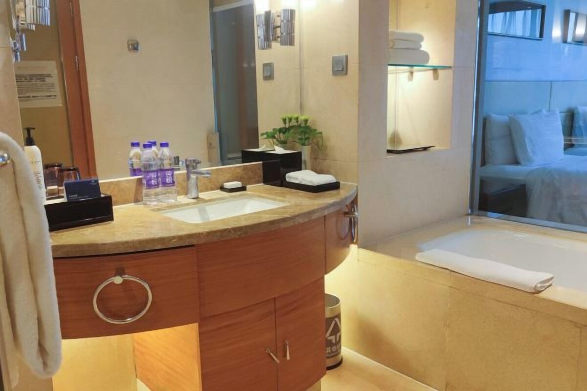A modern bathroom with a large sink, mirror, and a bathtub.