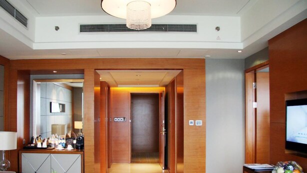A hotel lobby with a reception desk, a seating area with a sofa and a coffee table, a TV on the right, and a hallway leading to the rooms. - Wanda Realm Beijing (Beijing)