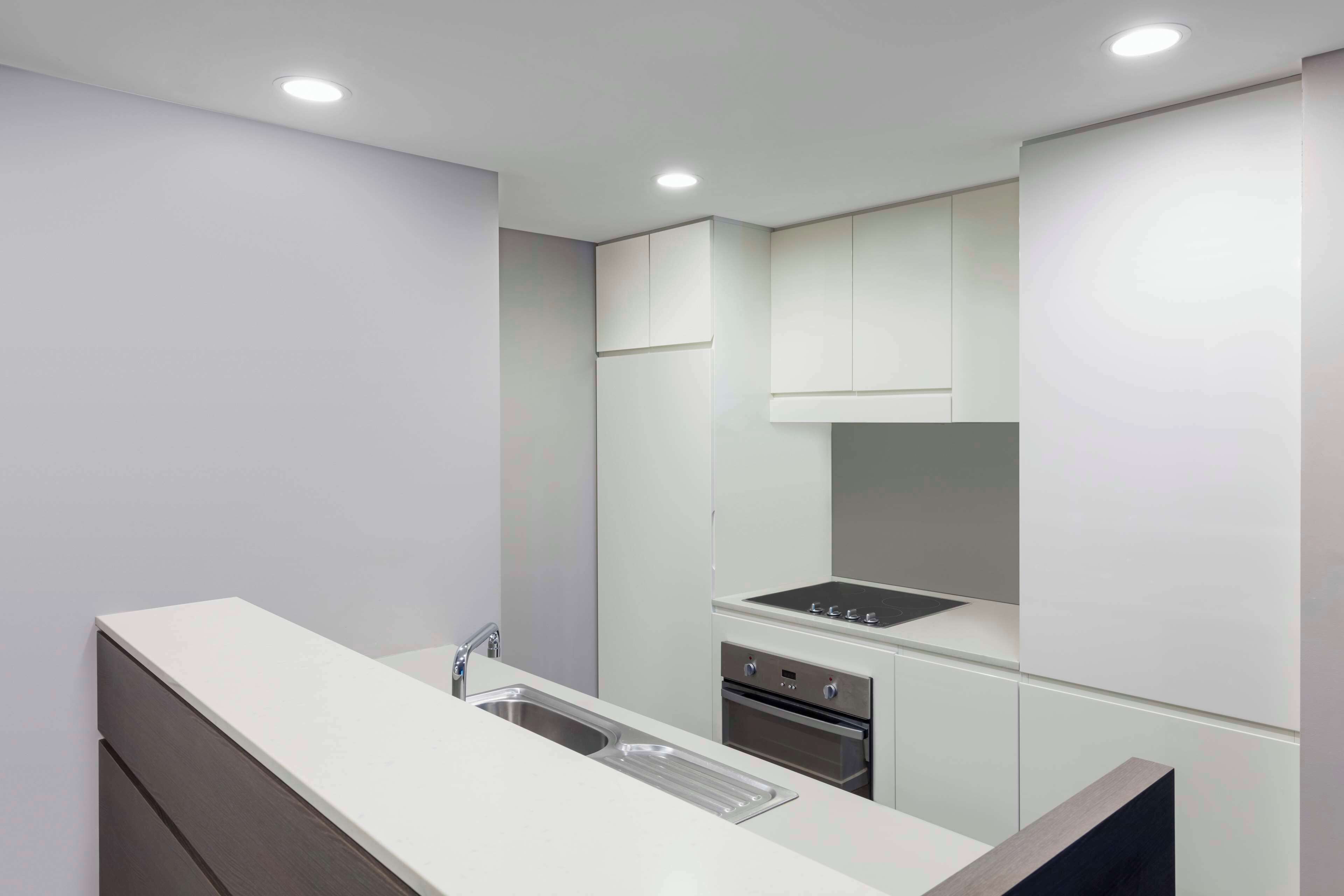 A modern kitchen with white cabinetry, a stainless steel sink, and a built-in oven.