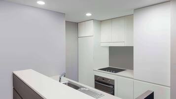 A modern kitchen with white cabinetry, a stainless steel sink, and a built-in oven.