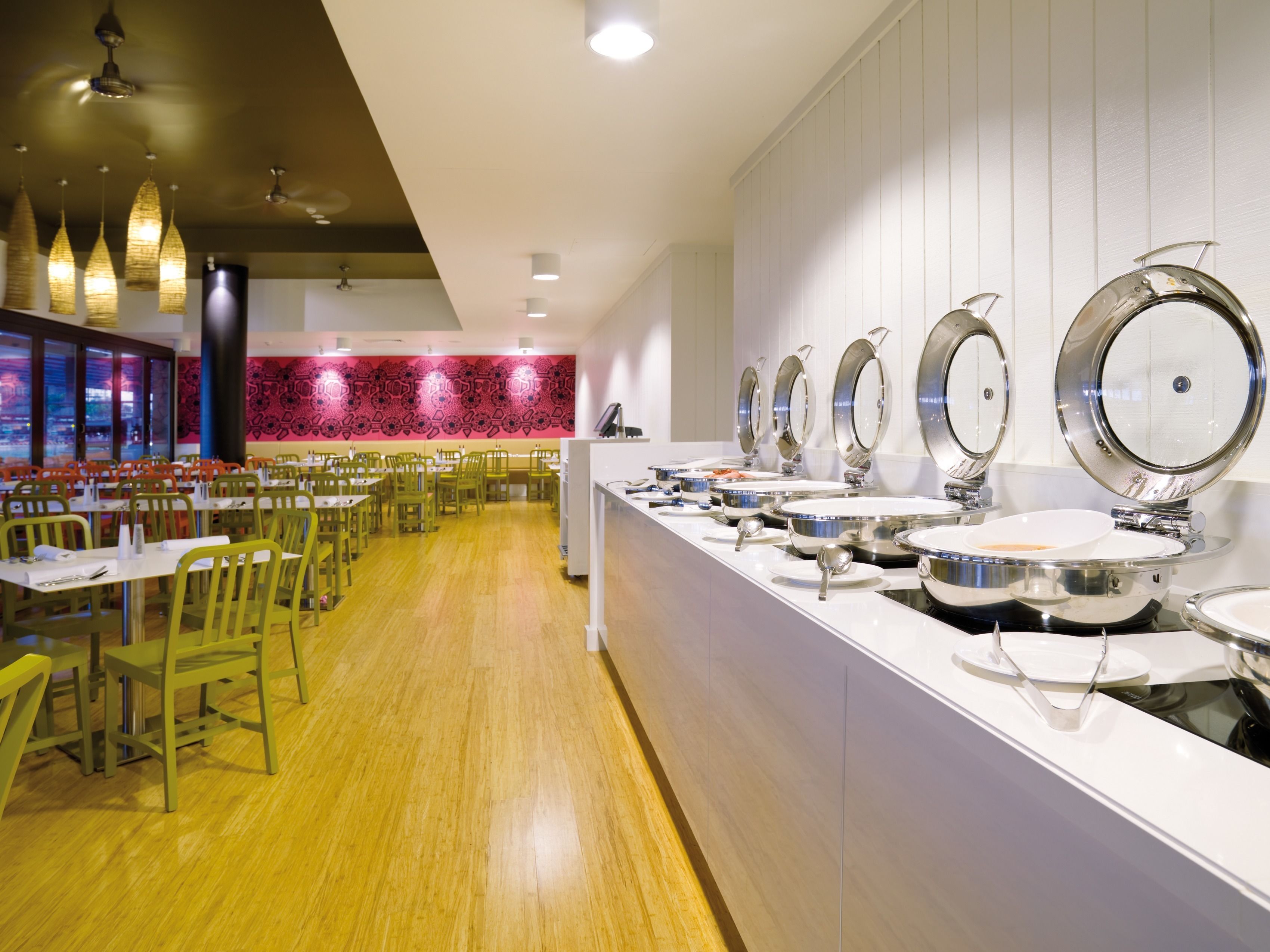 A buffet area with multiple serving stations, wooden tables, and chairs.