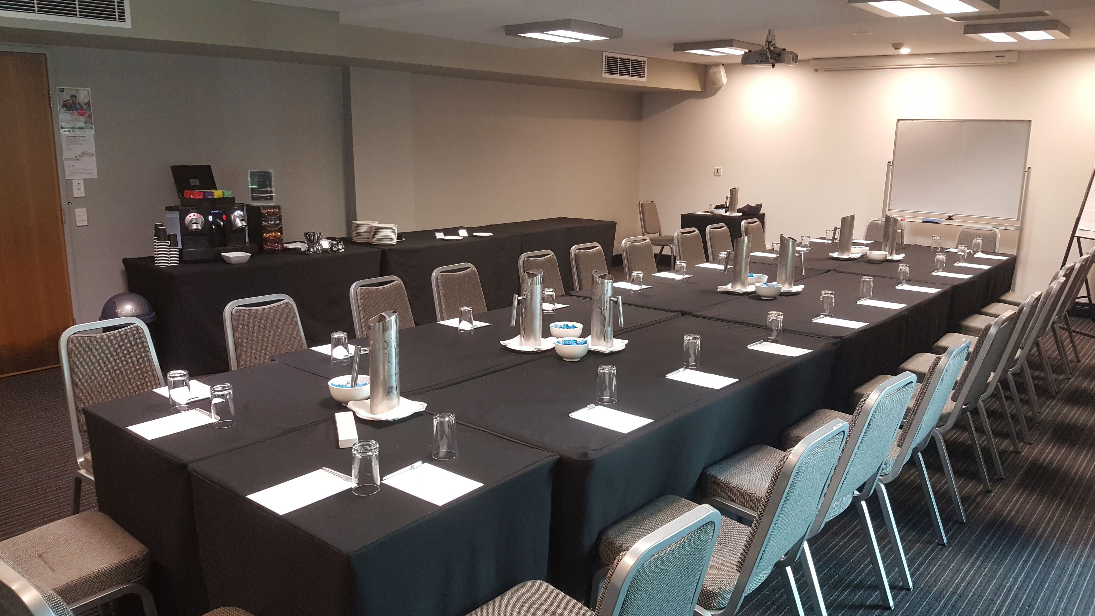 Une salle de conférence équipée de longues tables, de chaises et d’un tableau blanc.