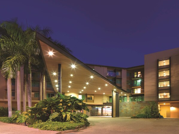 A modern hotel with a sloped roof, multiple balconies, and a well-lit entrance. - Adina Apartment Hotel Darwin Waterfront (Darwin)