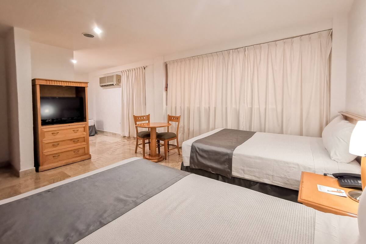 A hotel room with two beds, a TV, a desk, and a chair.