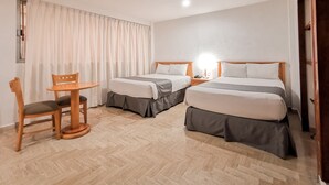 Habitación de hotel con dos camas, una mesita y una silla.