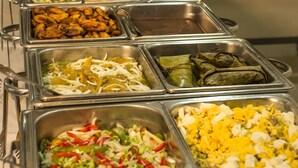 Un bufé con diversas opciones de comida en recipientes de metal.