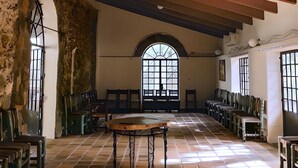 Un vestíbulo amplio con techo alto, vigas a la vista y un gran ventanal de arco.