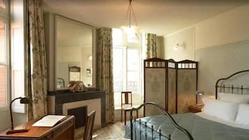 Um quarto com cama, escrivaninha, cadeira, espelho e guarda-roupa.