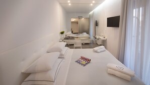 Una moderna camera d'albergo con un letto rifatto, una TV a schermo piatto, una scrivania con sedia e un ampio specchio.