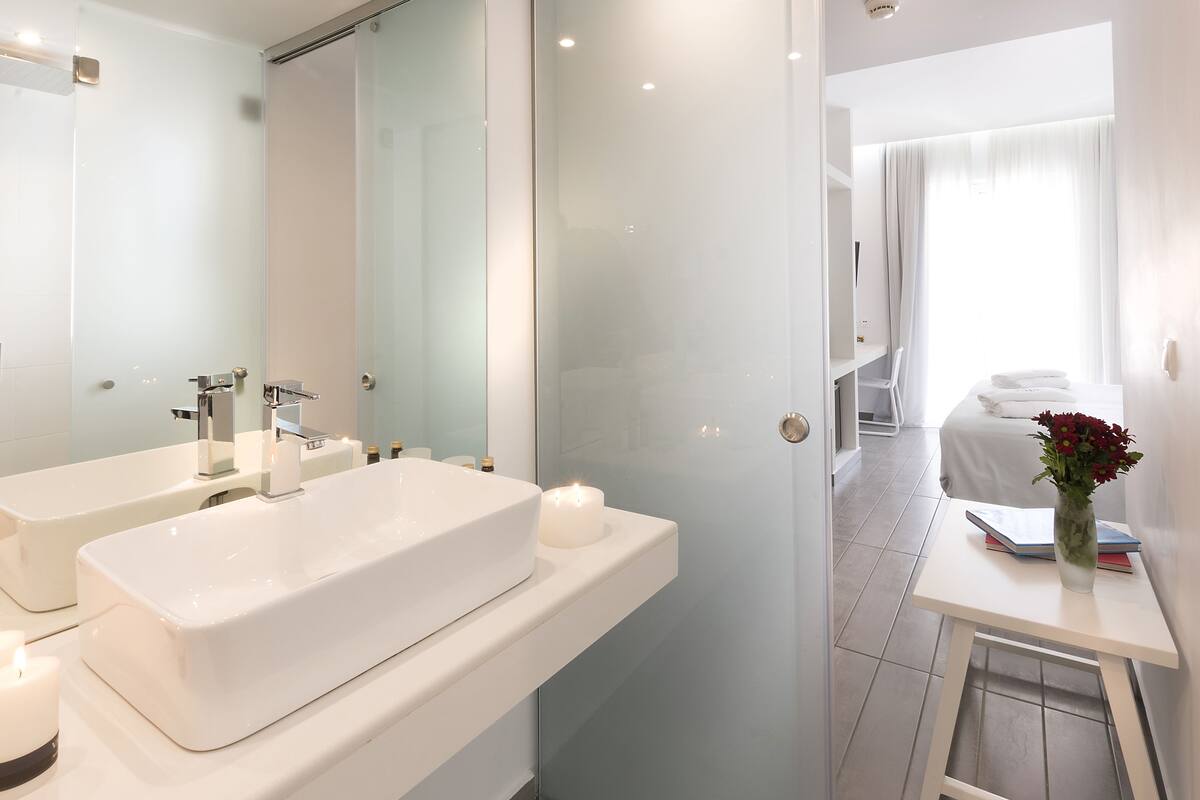 A modern bathroom with two sinks, a large mirror, and a glass shower enclosure.