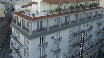 A multi-story hotel with balconies, air conditioning units, and potted plants.
