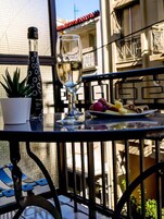 A balcony with a table set for dining, featuring a bottle, a glass, and a plate of food.