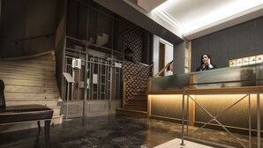 Un'area di accoglienza con una scala in legno, una reception e una teca in vetro.