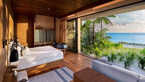 Un dormitorio moderno con una cama grande, una zona de estar y vistas al océano.