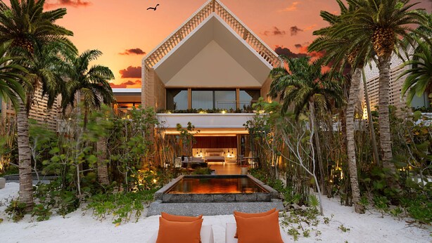 A modern building with a triangular roof, a pool, and palm trees.