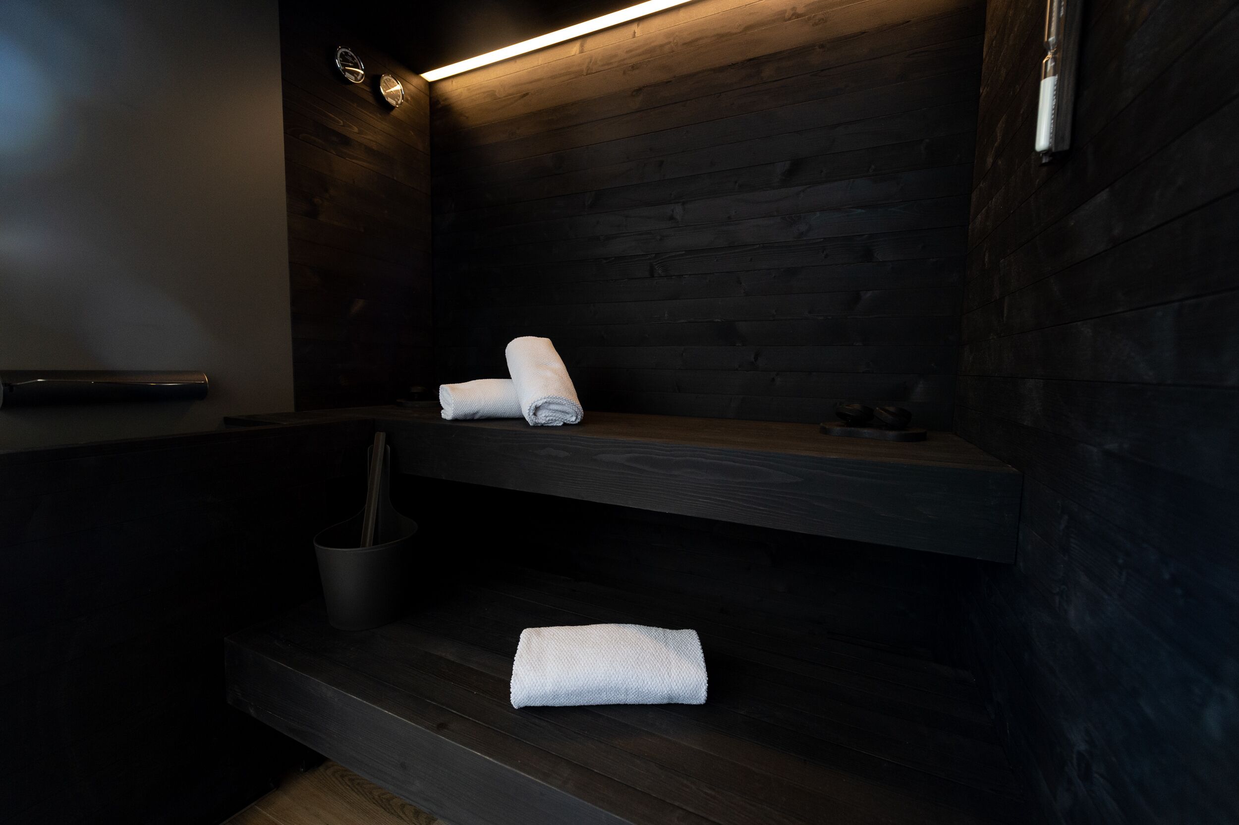 Ein modernes Badezimmer mit Holzwänden, einer eingebauten Ablage mit Handtüchern und einer kleinen Mülleimer.