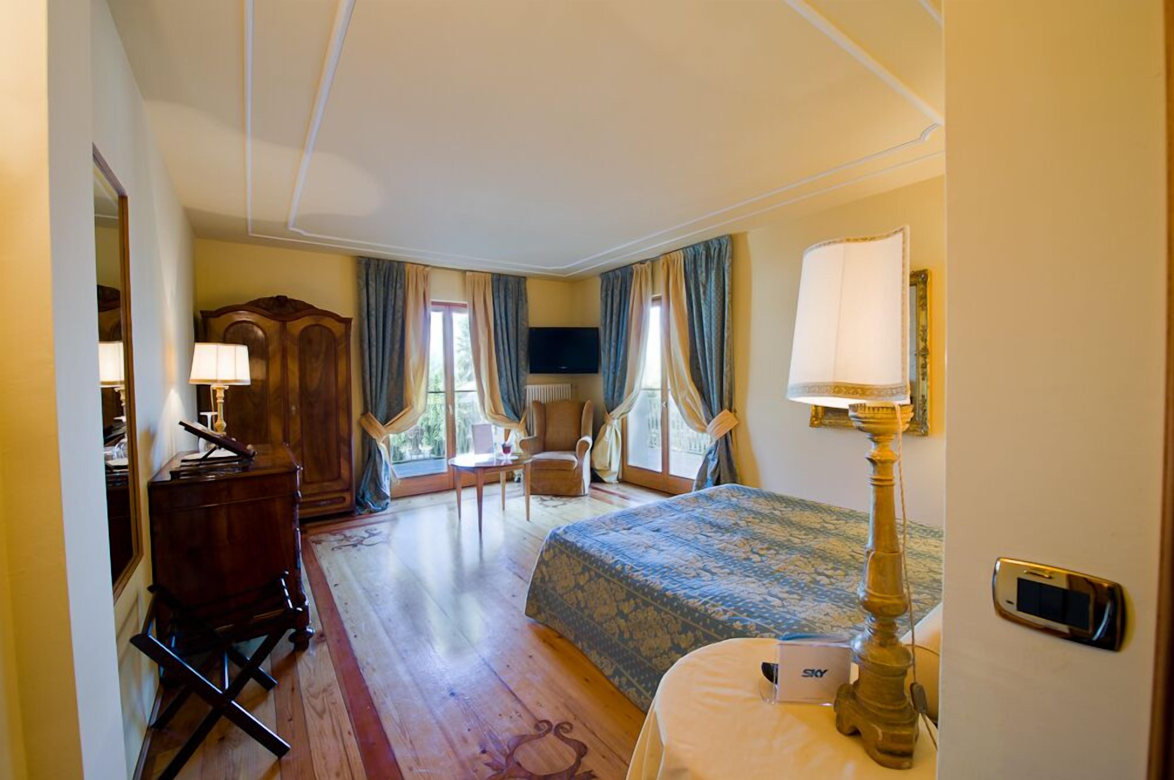Ein Hotelzimmer mit Bett, Schreibtisch, Stuhl, Fernseher und Lampe.