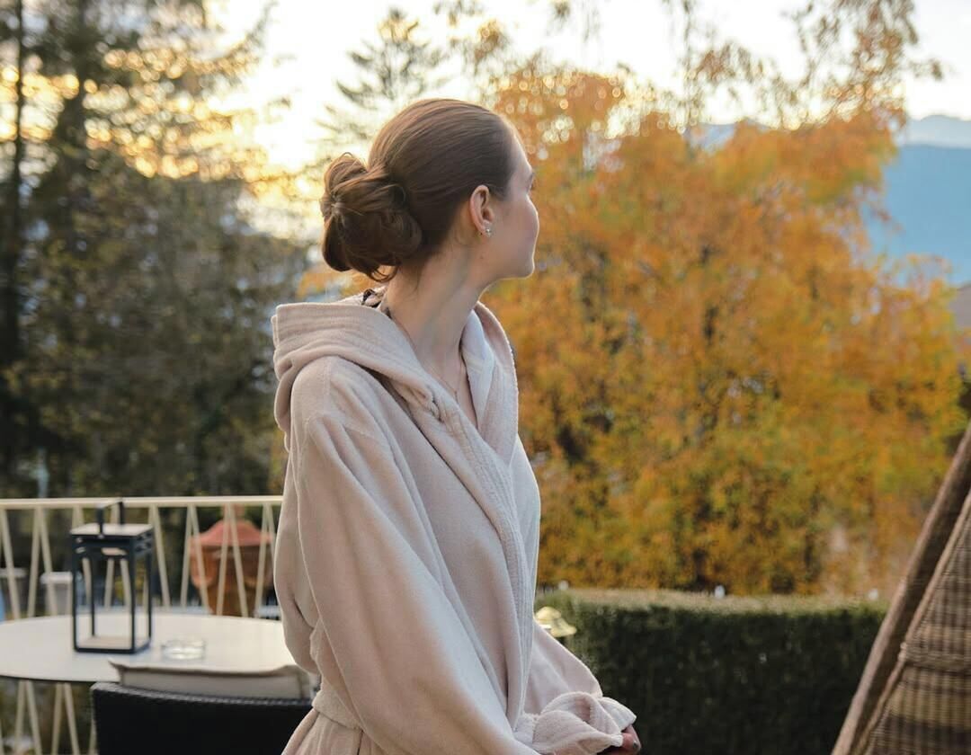 A person standing outdoors with autumn foliage in the background.