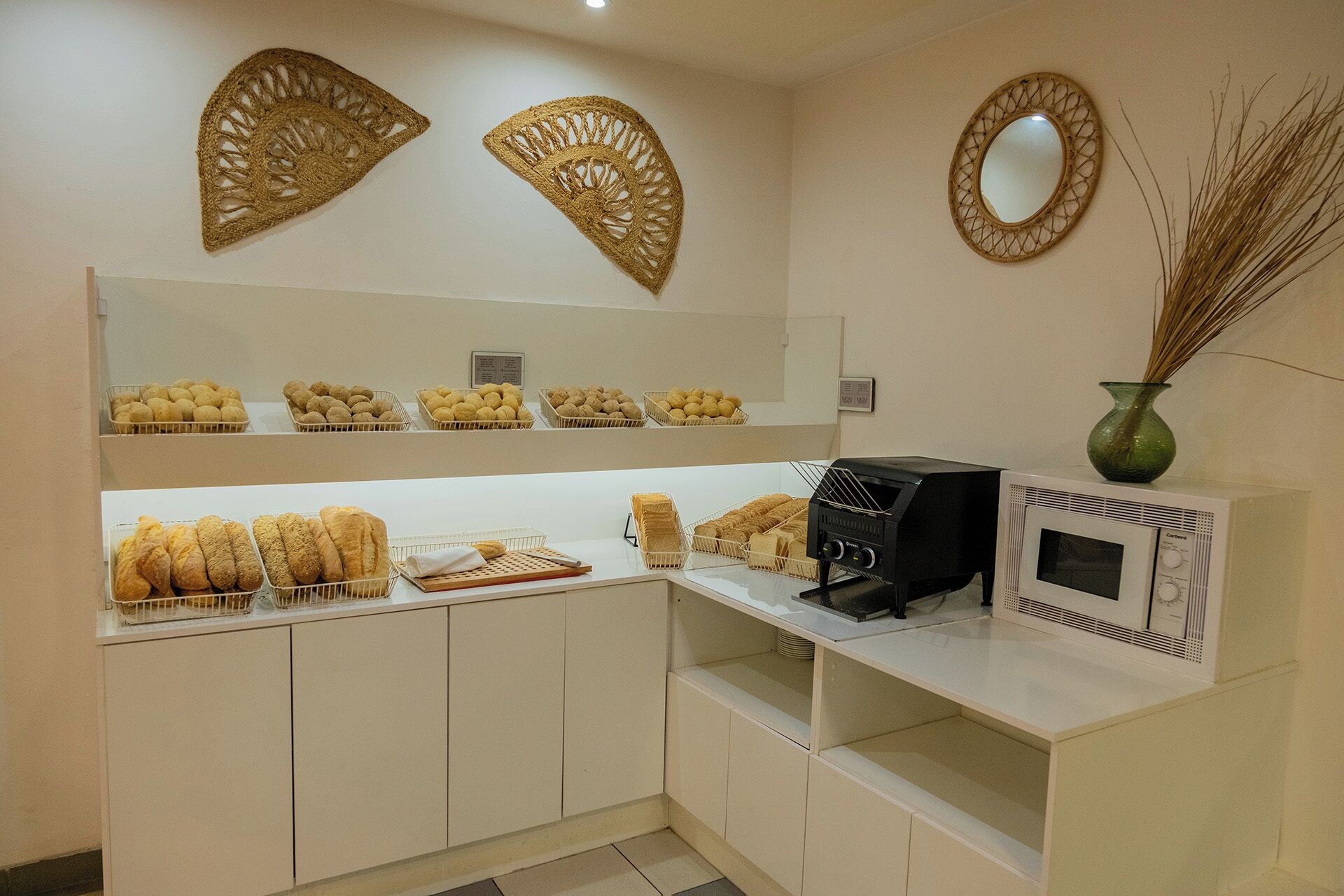 A kitchenette with bread, pastries, a coffee machine, and decorative wall art.