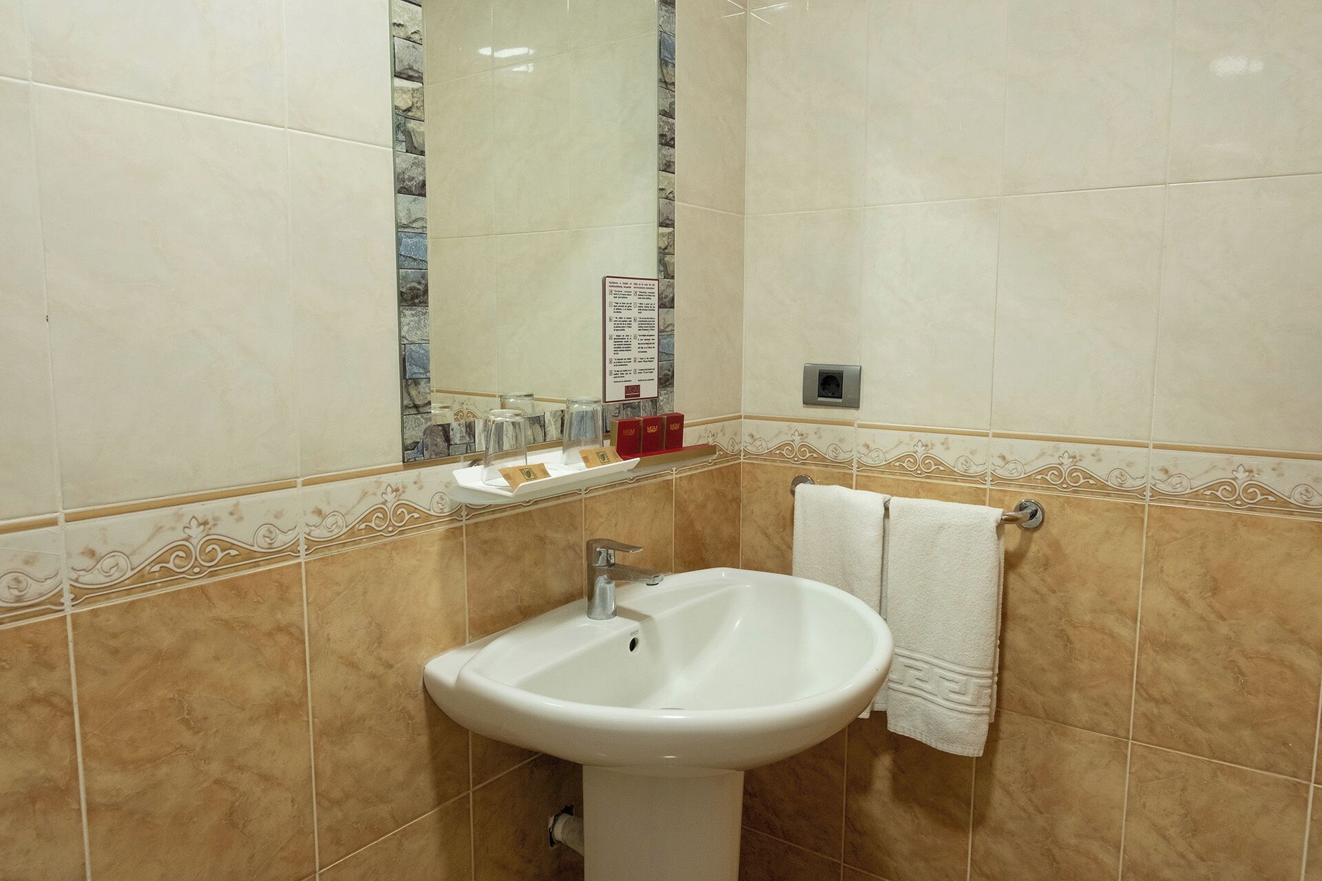 Une salle de bain avec un lavabo, un miroir et un porte-serviettes.