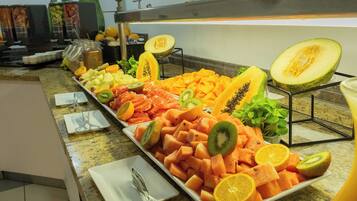Un bufé con diversas frutas y verduras, incluyendo melón, kiwi y rodajas de naranja.
