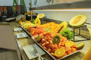 Un bufé con diversas frutas y verduras, incluyendo melón, kiwi y rodajas de naranja.
