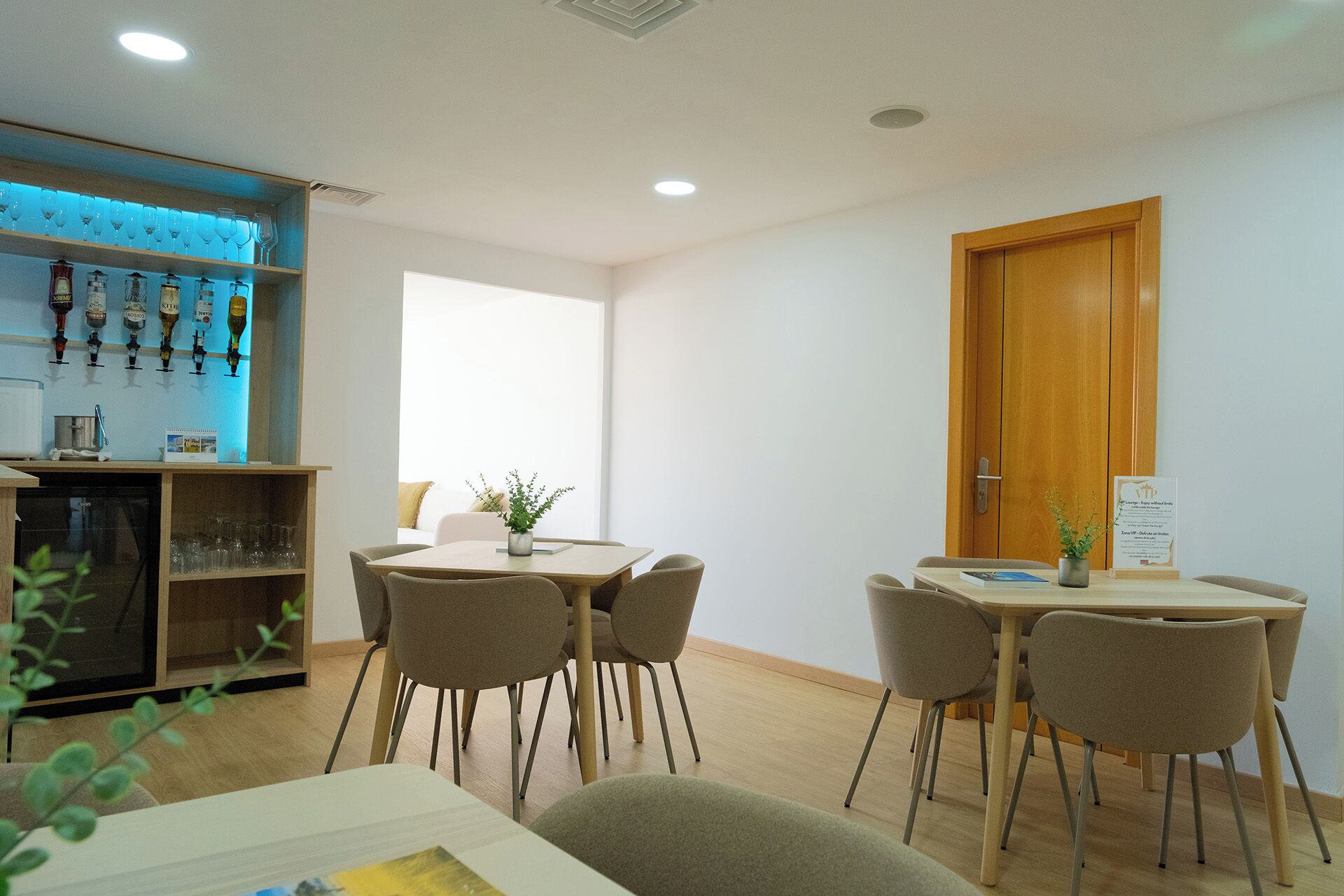 Een hotelkamer met een zithoek, een minibar en een houten deur.