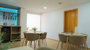 Une chambre d’hôtel avec un coin repas, un minibar et une porte en bois.