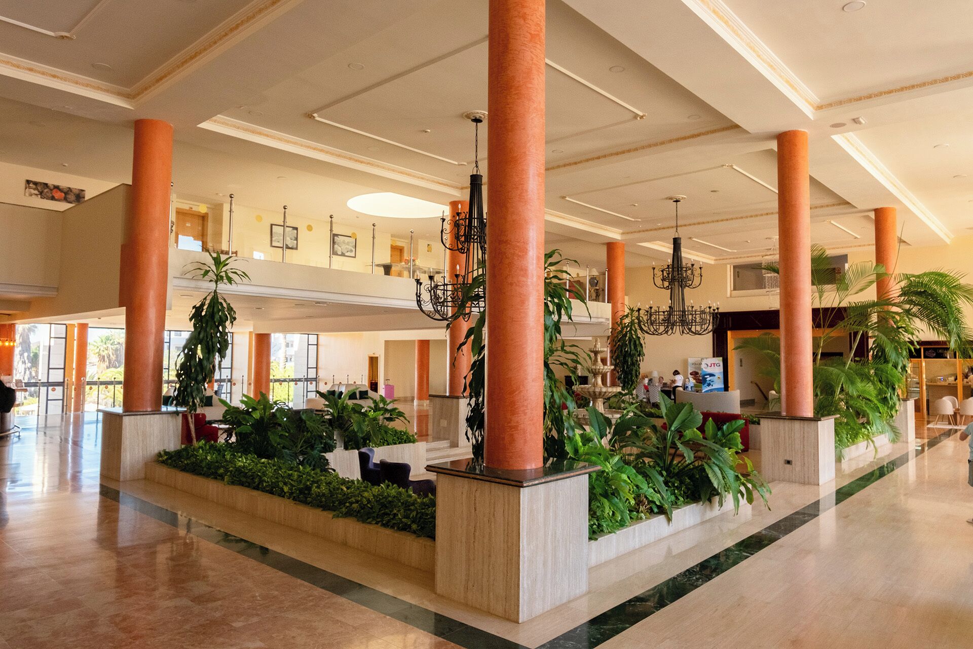 Un hall d’entrée spacieux, doté de hauts plafonds, de grandes colonnes et d’une fontaine centrale.