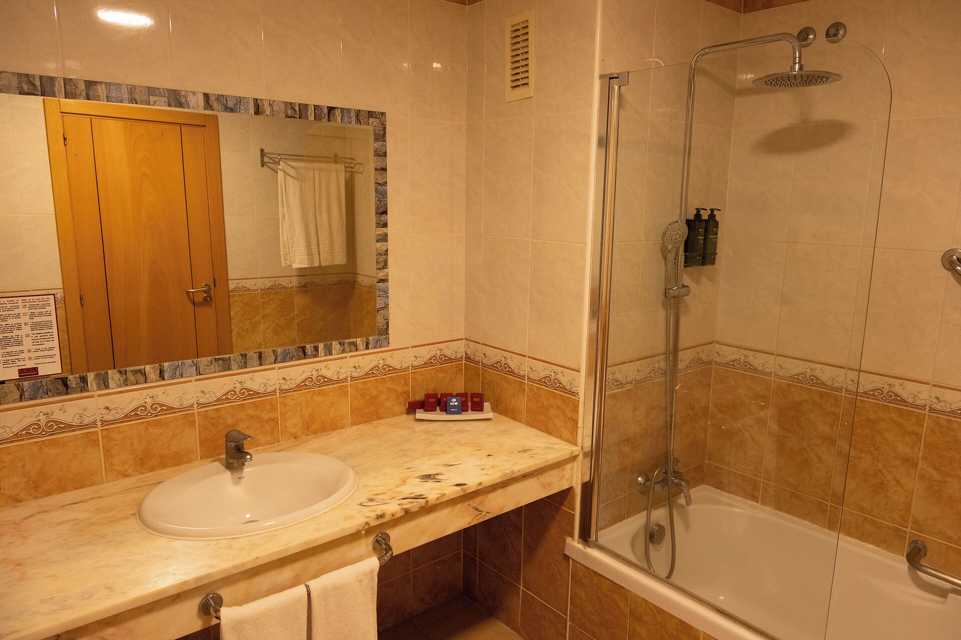 Un baño con lavamanos, espejo, ducha y bañera.