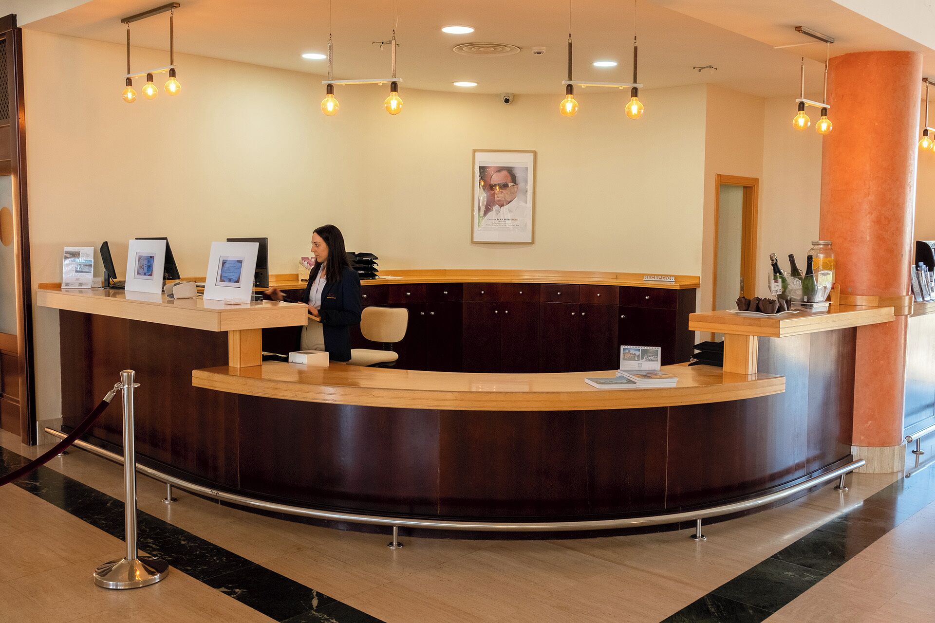 A reception desk with a receptionist, a framed picture on the wall, and a sign labeled 'RECEPTION'.