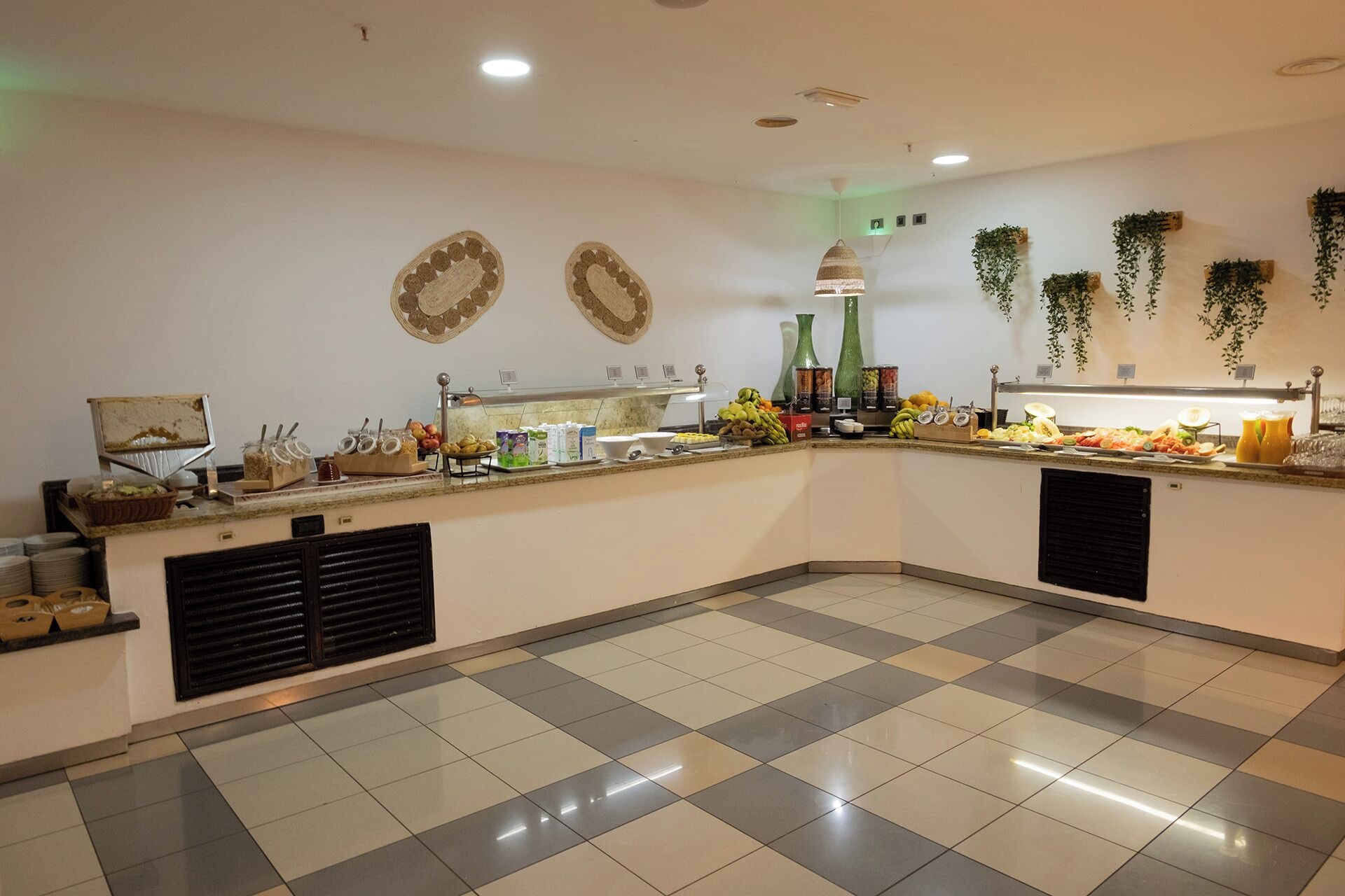 A buffet area with a checkered floor, a counter with food items, and decorative wall hangings.
