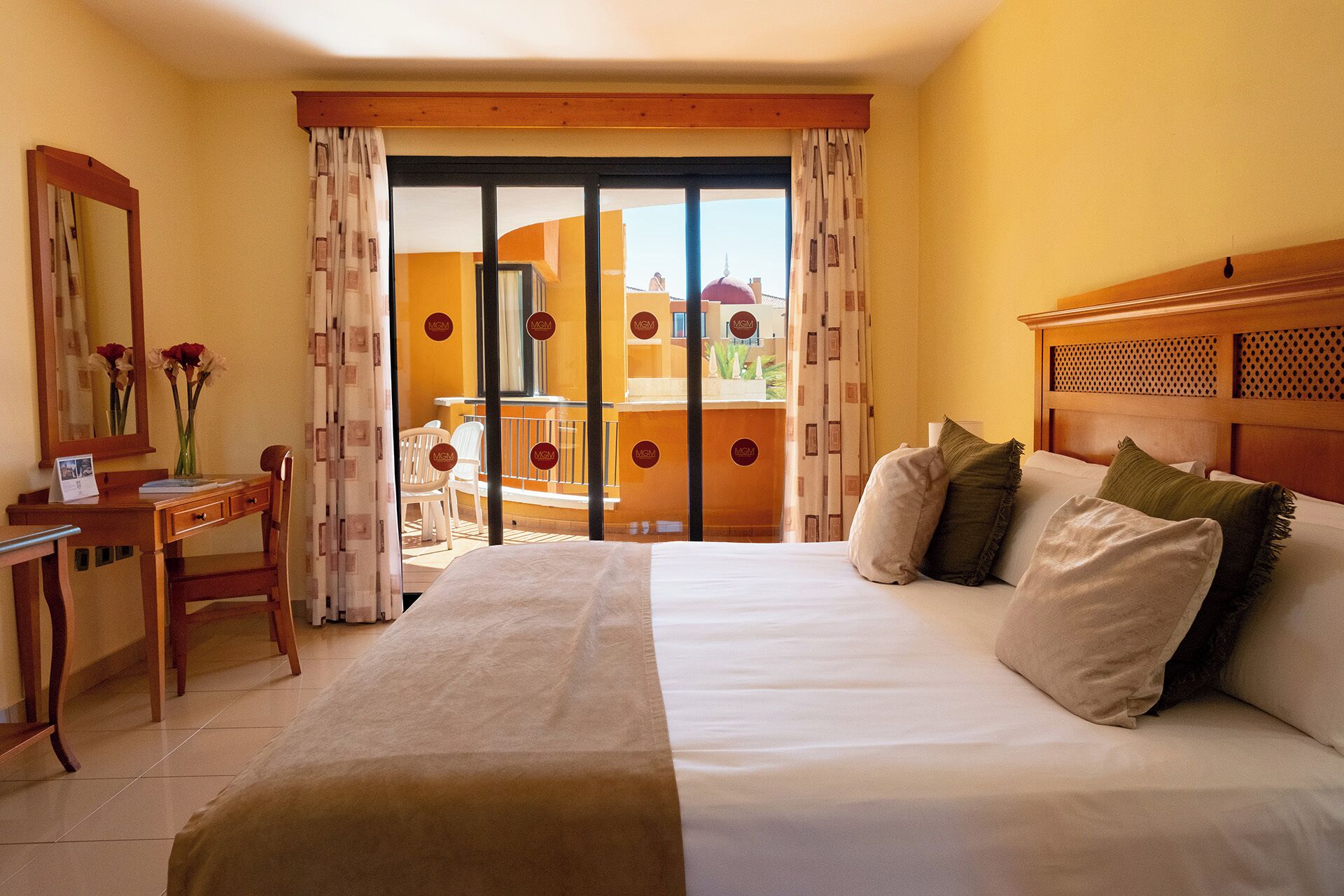 Une chambre d’hôtel comprenant un lit, un bureau avec une chaise, un miroir et une vue sur un bâtiment doté d’un dôme.