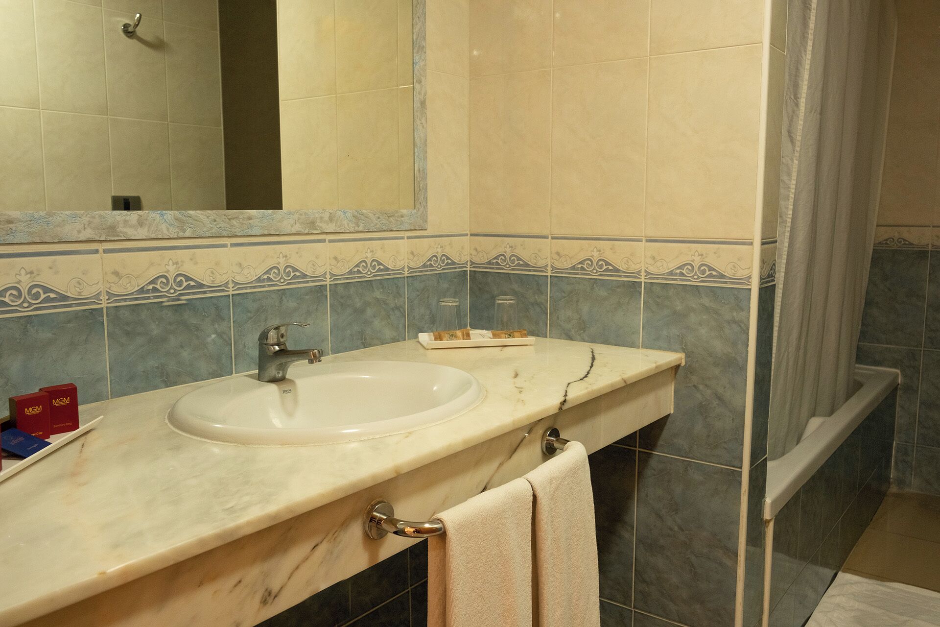 A bathroom with a sink, mirror, and shower.