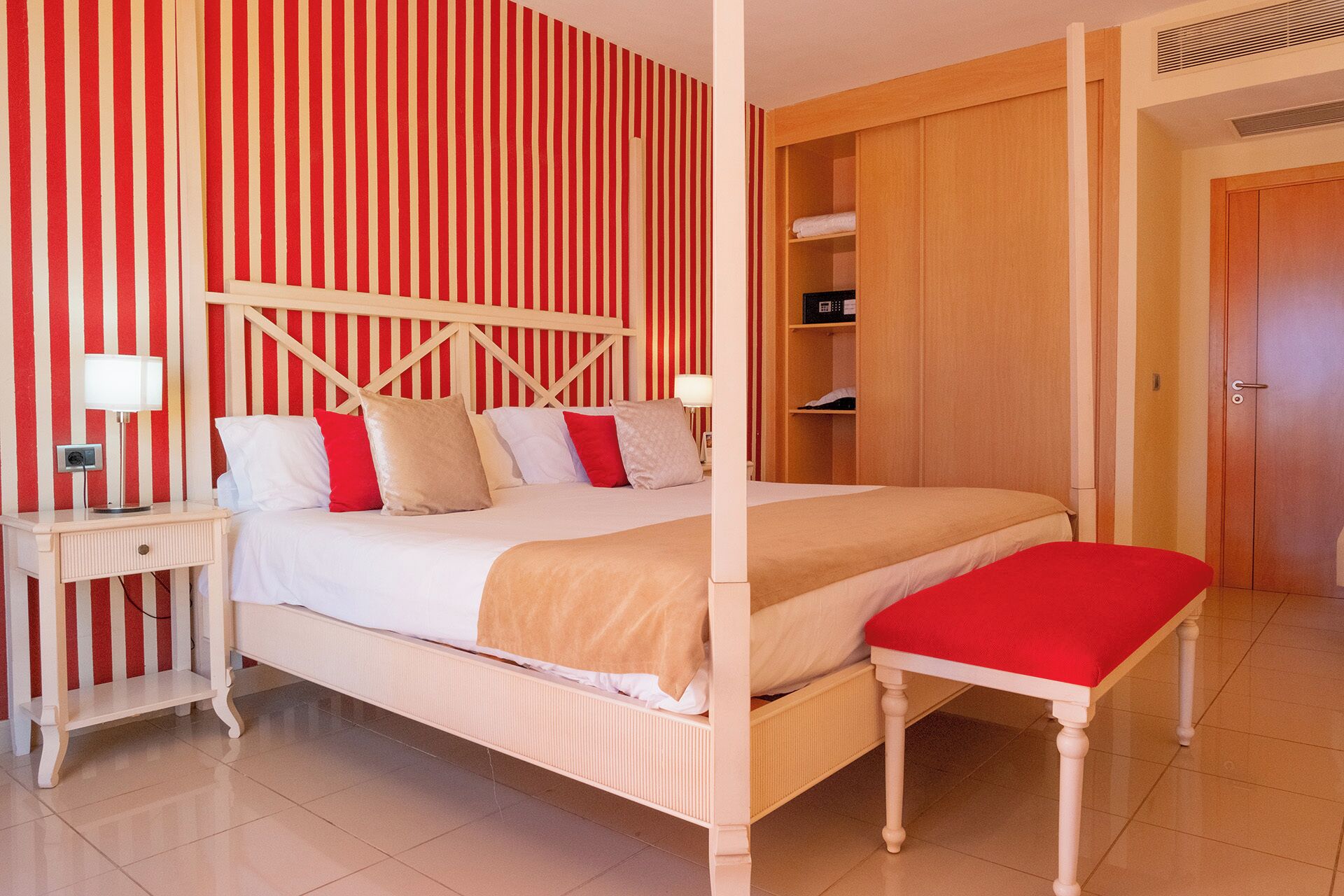 A hotel room with a bed, bedside table, lamp, and a wooden wardrobe.