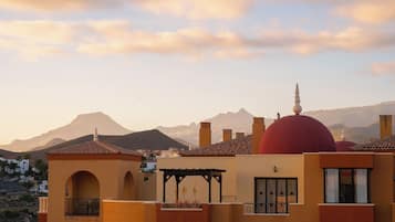A building with a red dome, multiple chimneys, and a mountainous backdrop.