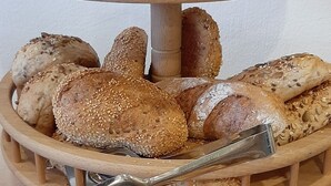 A multi-tiered wooden bread display with various types of bread, including croissants and seeded rolls. - Hotel Das Landhaus (Hoechenschwand)