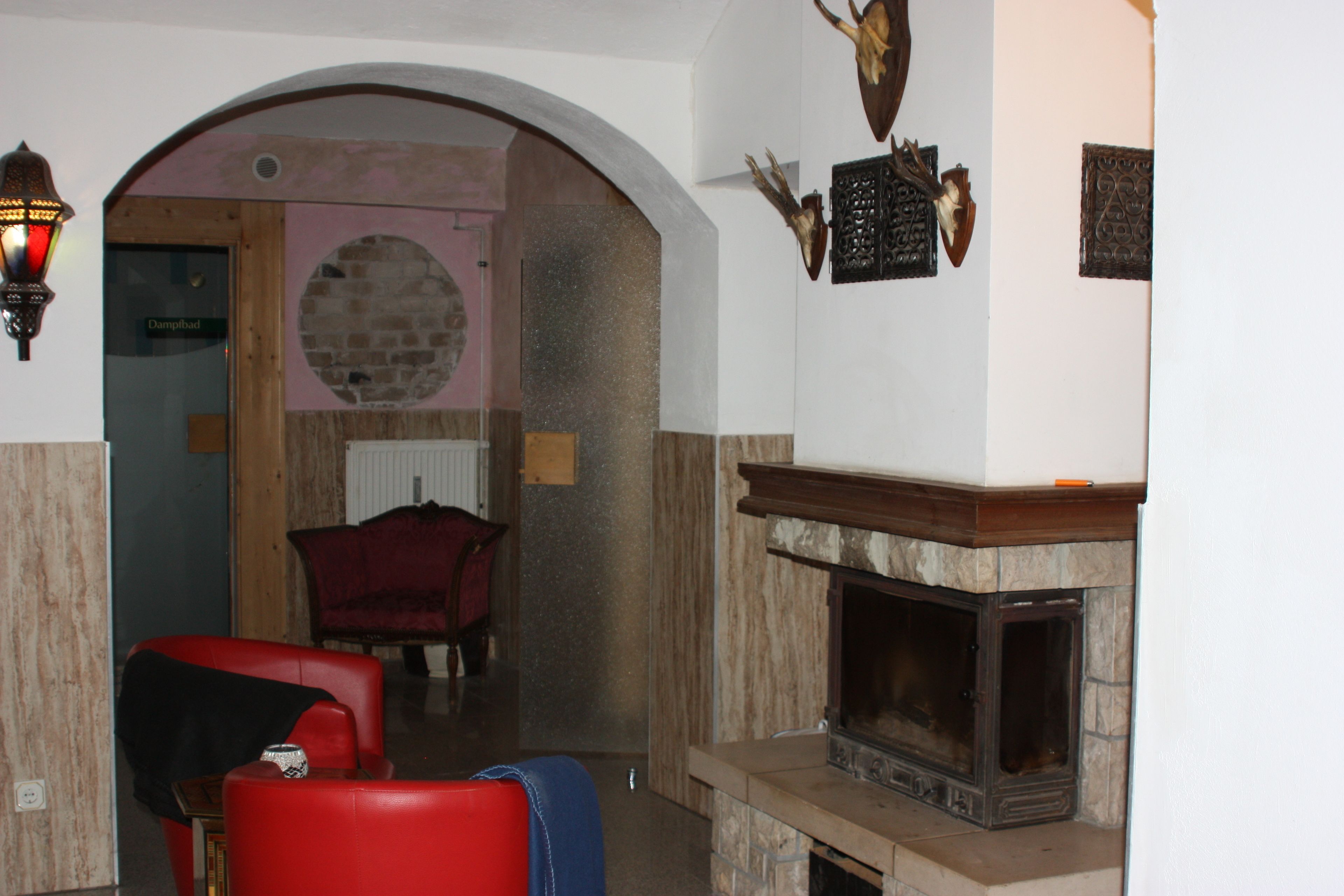 A room with a fireplace, a red armchair, a wooden door, and a stone wall.