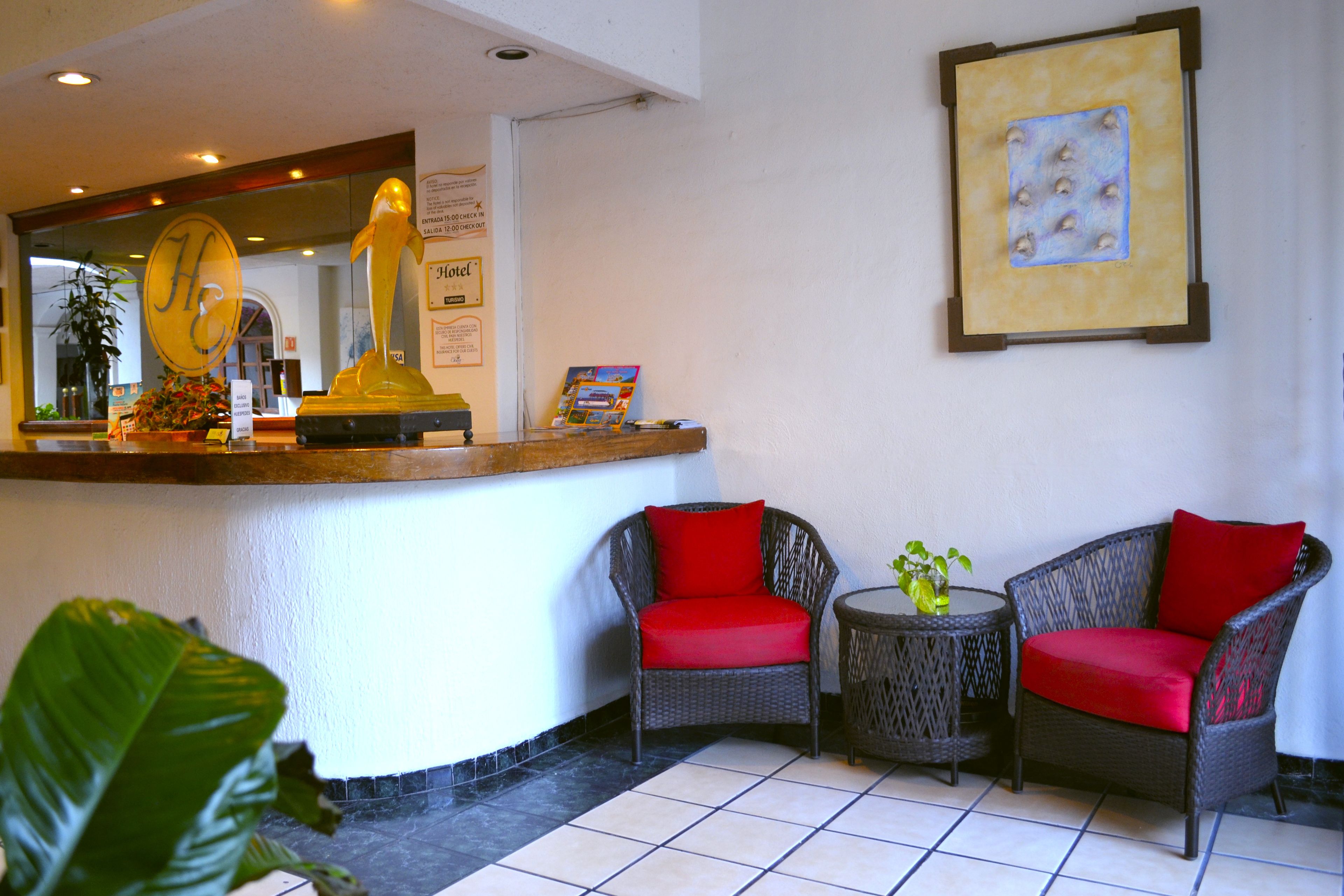 A reception area with wicker chairs, a small table with a plant, and a framed artwork on the wall.